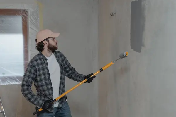 Painter rolling grey paint onto an interior wall in Wichita